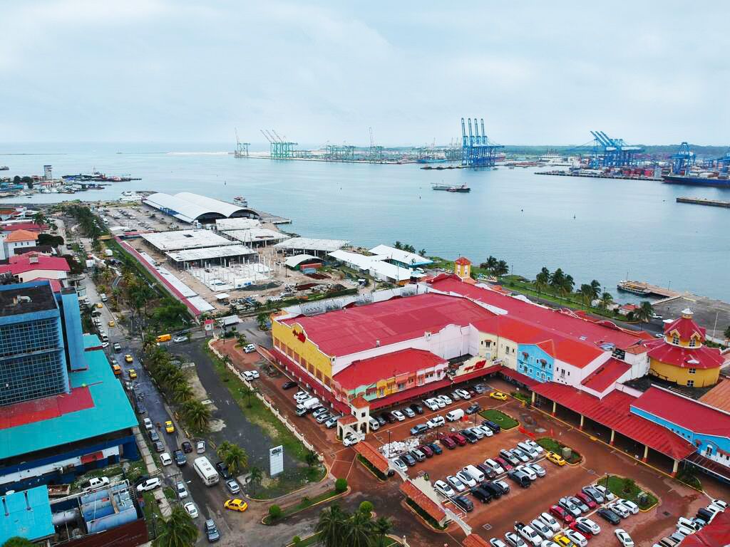 An aerial view of a coastal industrial area with warehouses and a large parking lot.