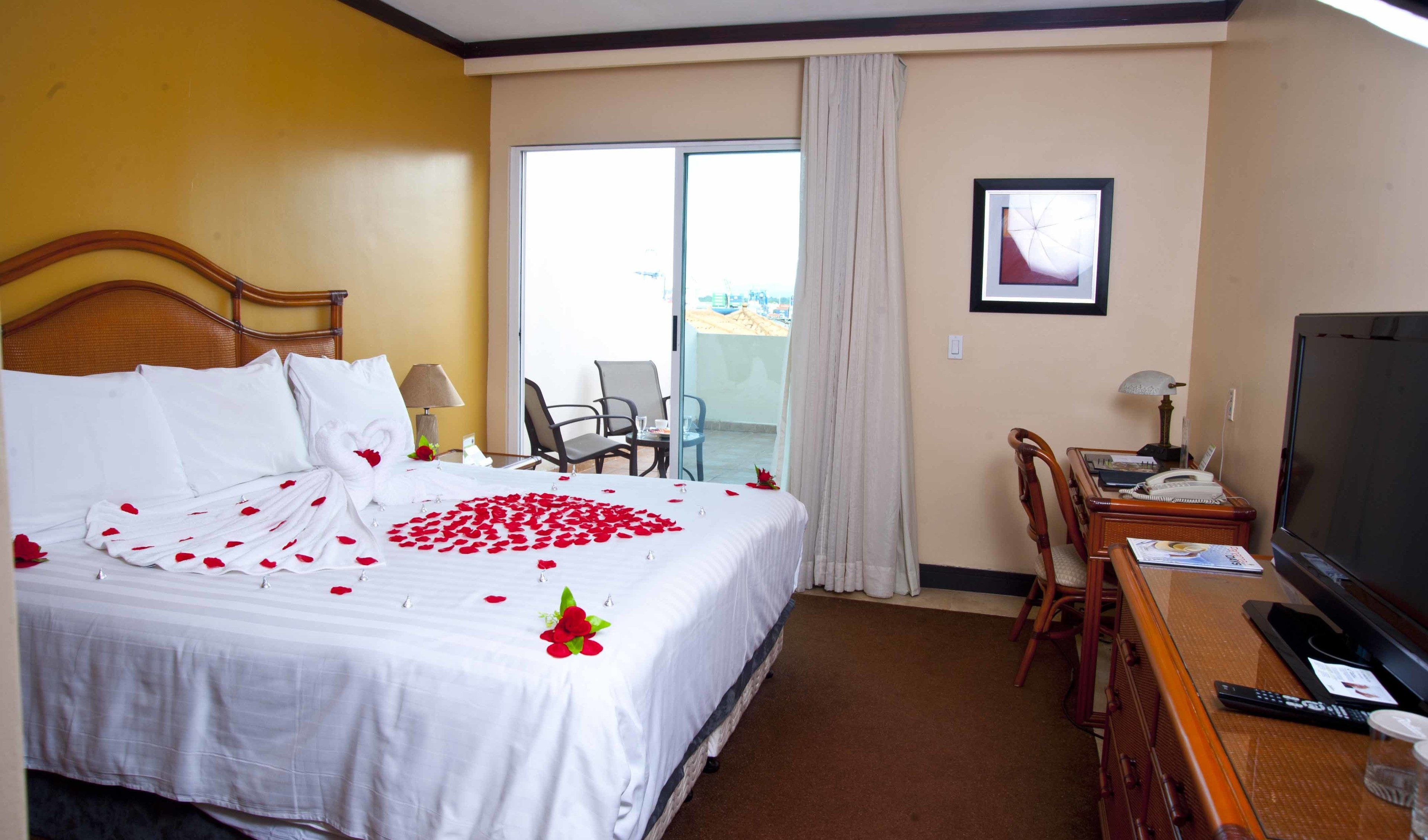 Habitación de hotel con cama, televisor, escritorio y vista al exterior.