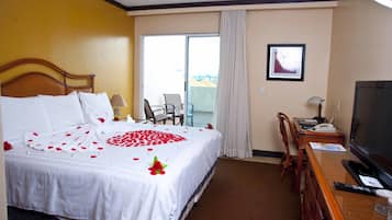 Habitación de hotel con cama, televisor, escritorio y vista al exterior.