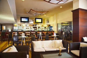 Zona de bar con televisor, barra y disposición de asientos.