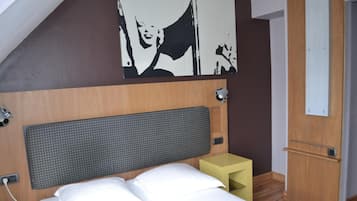 A neatly arranged hotel room with a bed, a small bedside table, a wall-mounted light, and a door.
