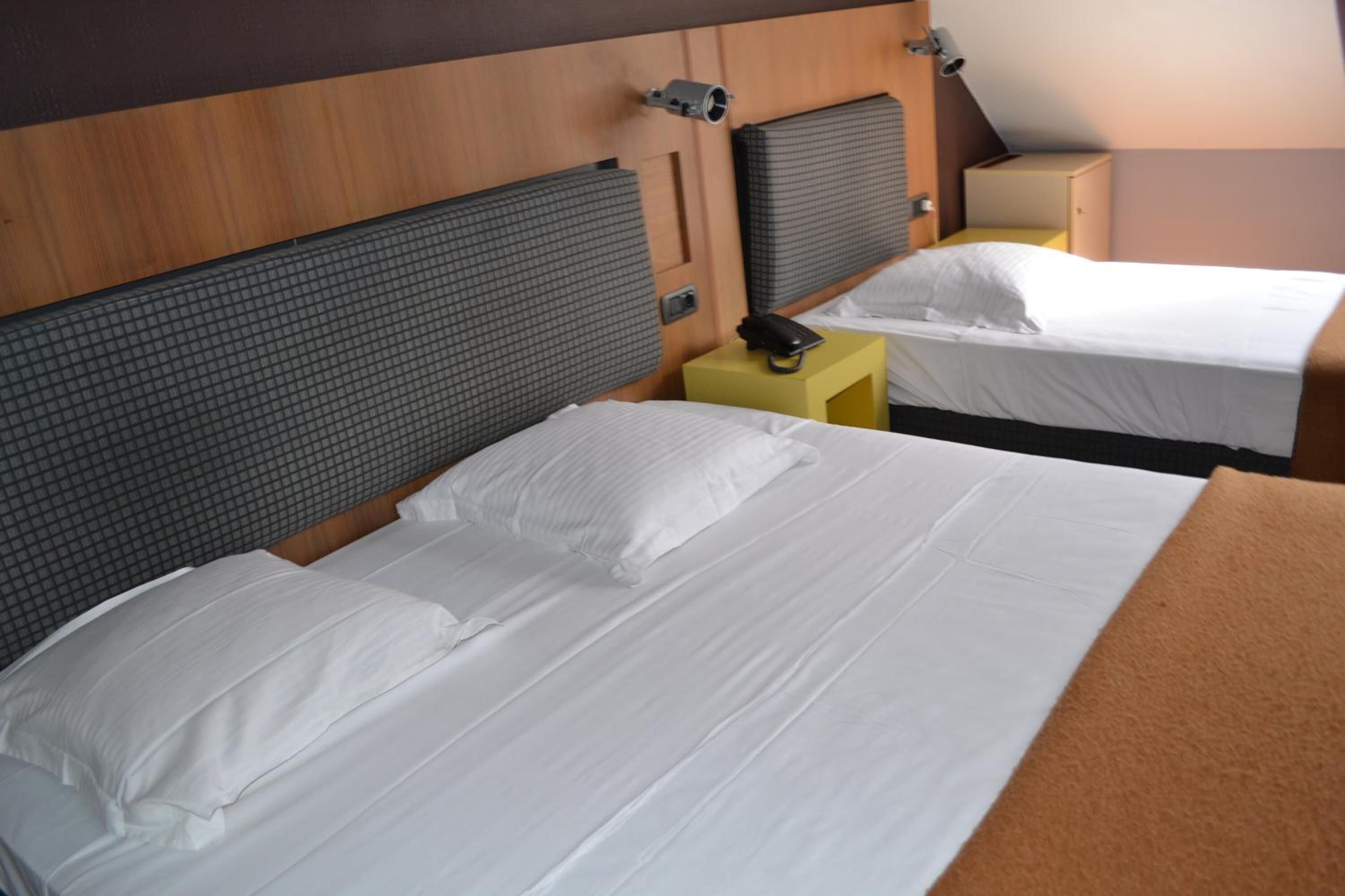 Una habitación de hotel con dos camas, cada una con cabecero y mesita de noche.