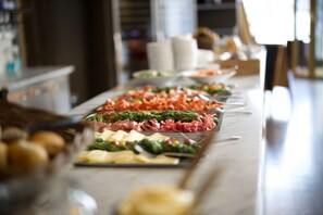 Un bufé con diferentes opciones de comida, incluyendo carnes, quesos y verduras.
