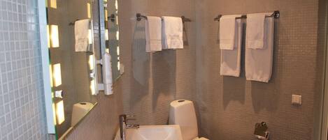 Un baño con lavamanos, espejo y dos toallas colgadas en la pared.