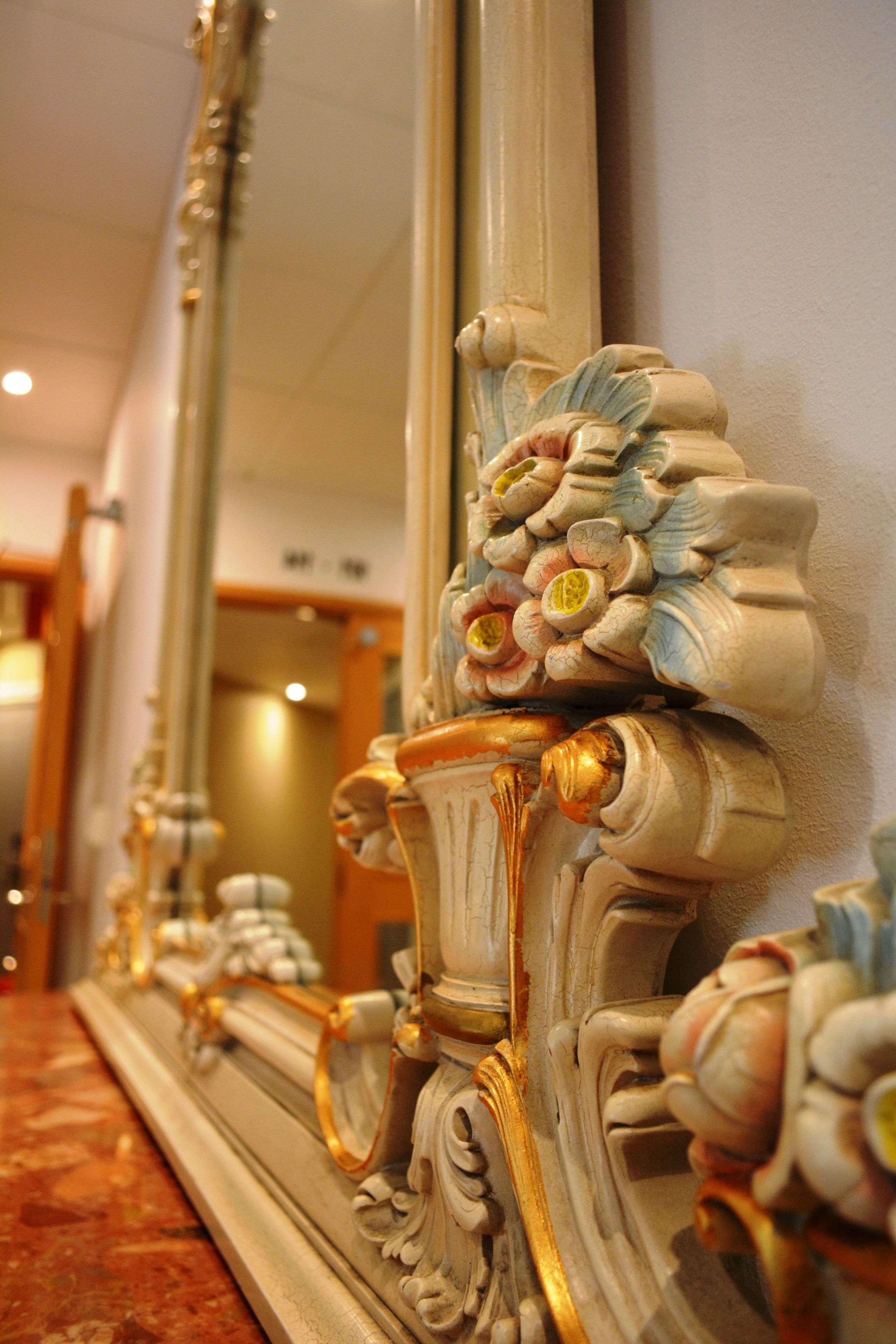 Ein Spiegel mit aufwendigen floralen Verzierungen und goldenen Akzenten.