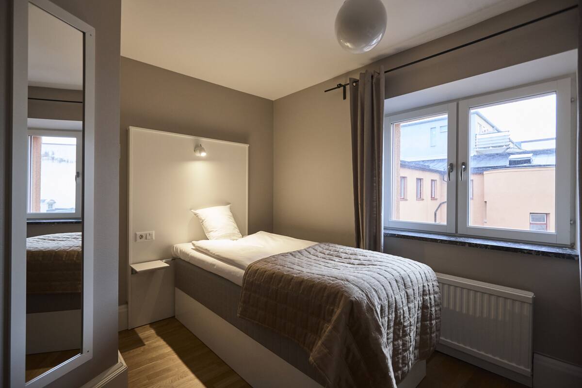 Ein Schlafzimmer mit Bett, Fenster und Heizkörper.