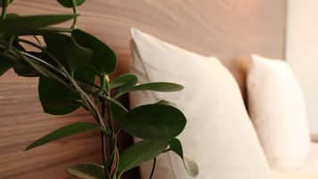 Primer plano de una planta con hojas verdes y un cabecero de madera con almohadillas blancas.