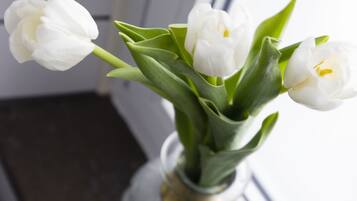 Un vase rempli de tulipes blanches, posé sur un rebord de fenêtre.