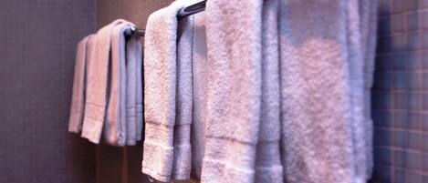 A row of neatly folded towels hanging on a rack in a bathroom with a tiled wall.