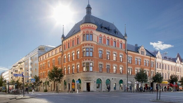 Un edificio histórico con una destacada torre en esquina y ventanas arqueadas.