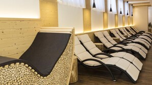 A row of sun loungers with cushions, a wooden wall, and hanging pendant lights. - Hotel Tschurtschenthaler (Dobbiaco)