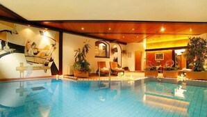 An indoor swimming pool with lounge chairs and a staircase. - Hotel Tschurtschenthaler (Dobbiaco)