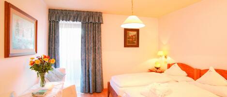 Une chambre d’hôtel avec deux lits, un bureau avec une chaise, un vase de fleurs et un tableau au mur.