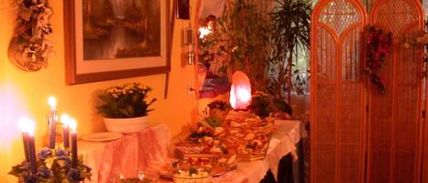 A dining table with various dishes and a lit candle centerpiece.