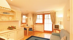 A compact living space with a kitchenette, dining area, and a seating area with a TV. - Hotel Tschurtschenthaler (Dobbiaco)