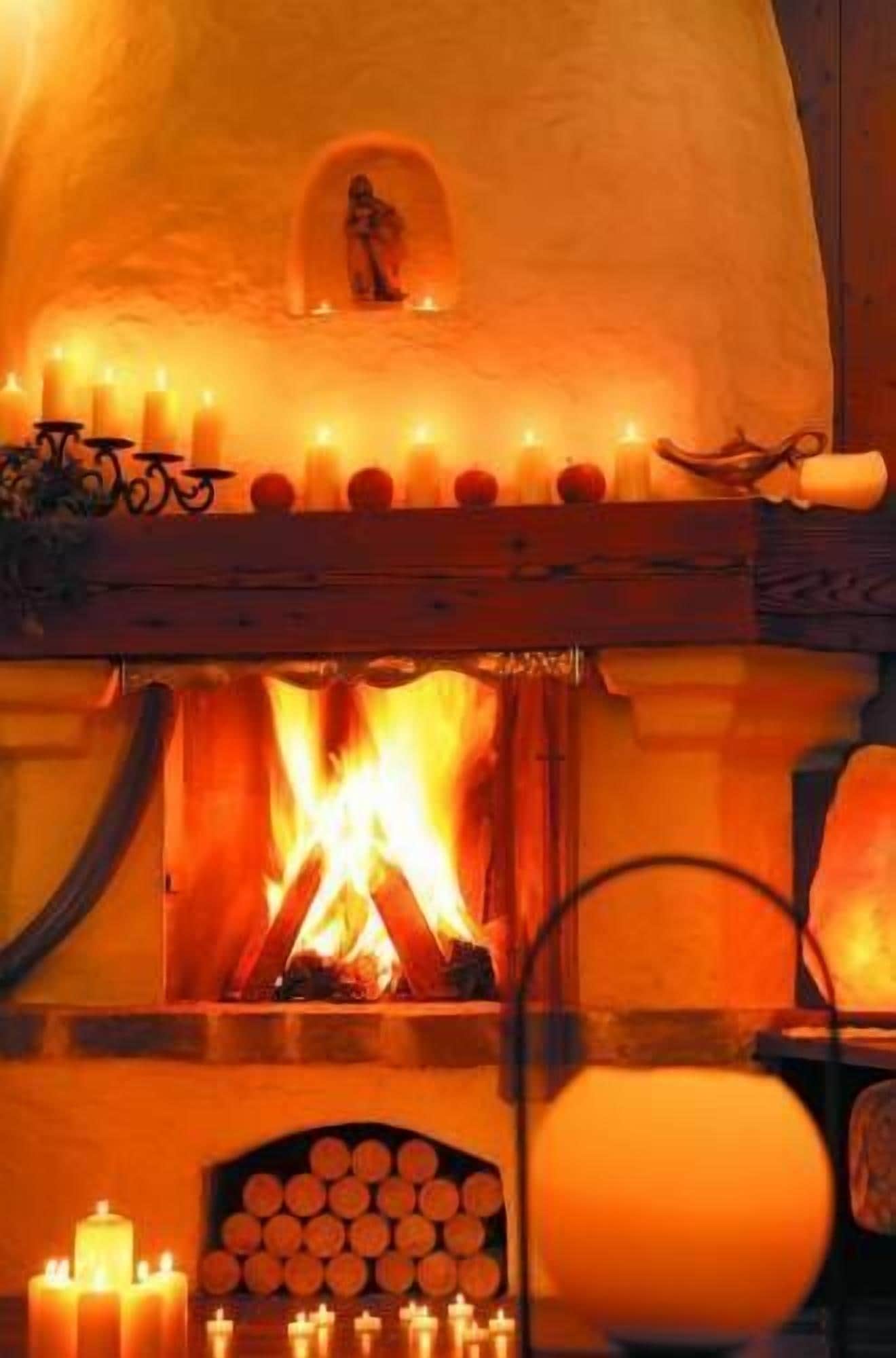 A traditional fireplace with a stone arch, a small window above the fire, and a row of candles on the mantel.
