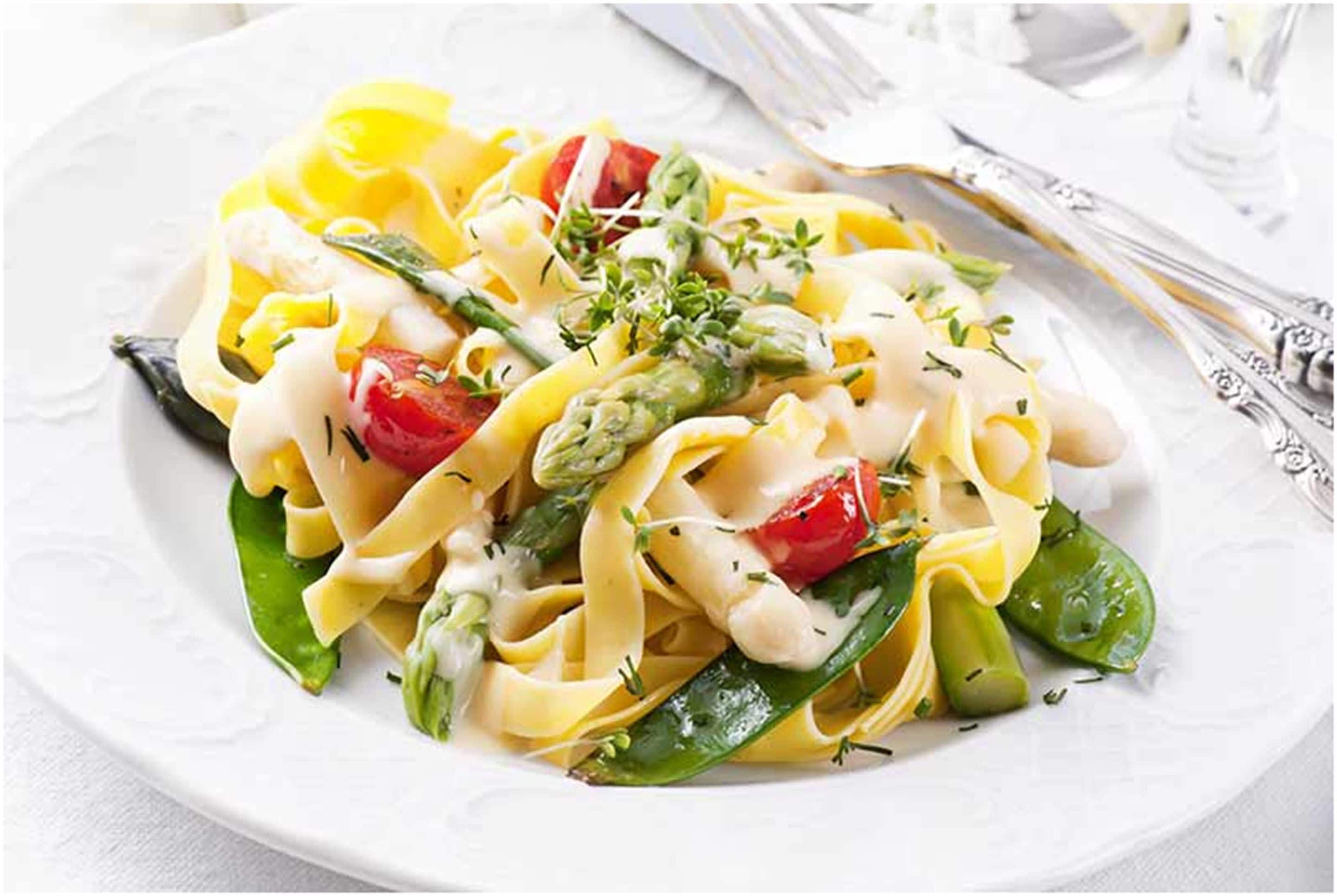 Un plato de pasta con verduras y hierbas.