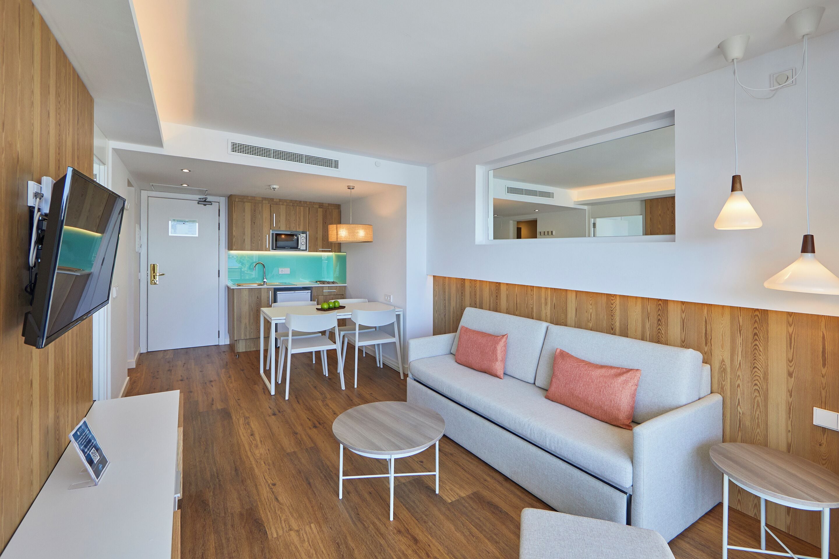 Una sala de estar moderna con sofá, mesa de centro y un comedor con mesa y sillas.