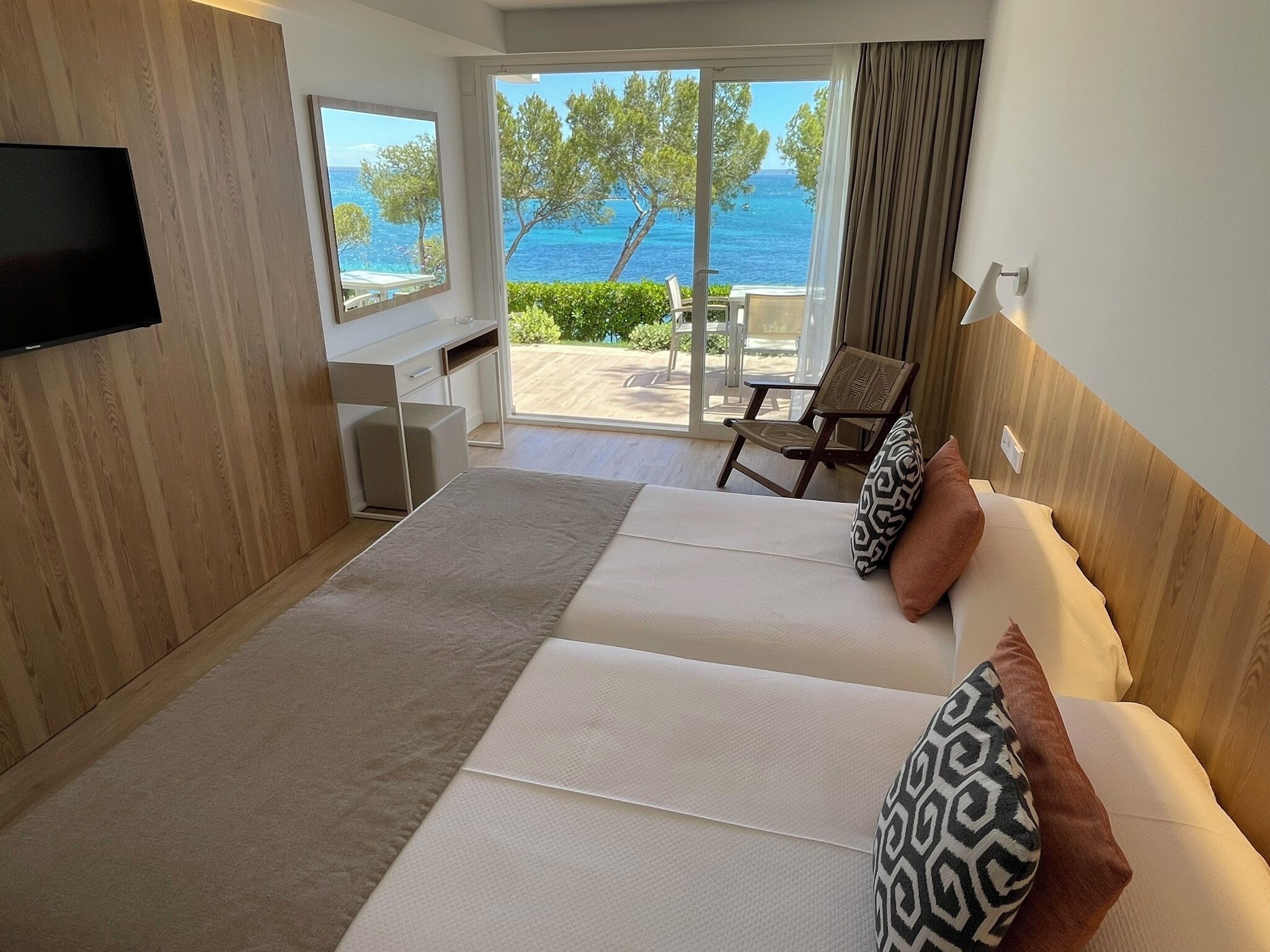 Une chambre d’hôtel avec un grand lit, une télévision, un bureau et une vue sur la mer.