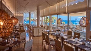 Un ampli restaurant amb sostres alts, grans finestres que donen vista a l'oceà i il·luminació penjant de vimetra moderna.