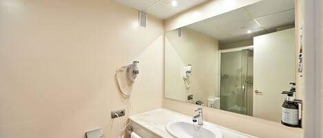 A modern bathroom with a white sink, a large mirror, and a towel rack.