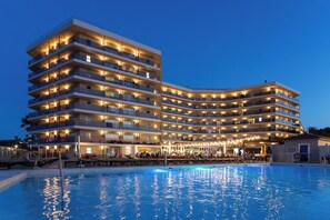 Un hotel de varios pisos con balcones, piscina y zona de bar.