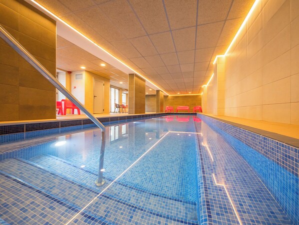 Una piscina interior con paredes de azulejos azules y una vista despejada del área de la piscina.