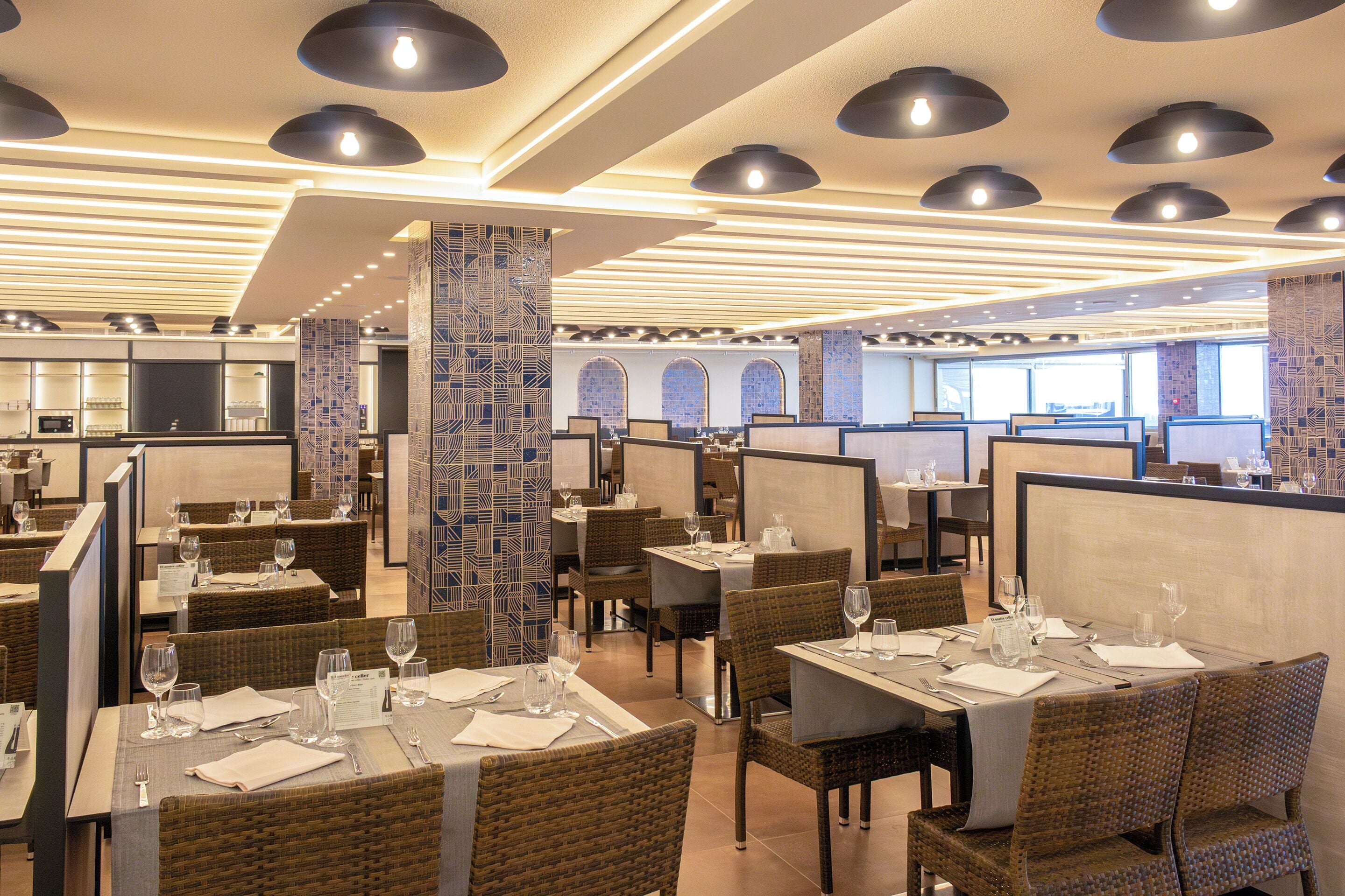 A restaurant with high tables and chairs, partitioned booths, and a modern ceiling design.