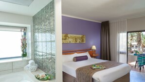 Habitación de hotel con una cama grande, una bañera y vistas al exterior.