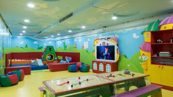 A children's play area with colorful furniture, a play table, and a television screen.