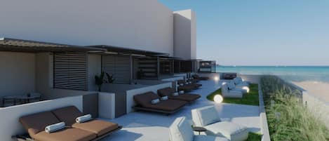 Un área de lounge en la azotea con sillones de sol y vistas a la playa.