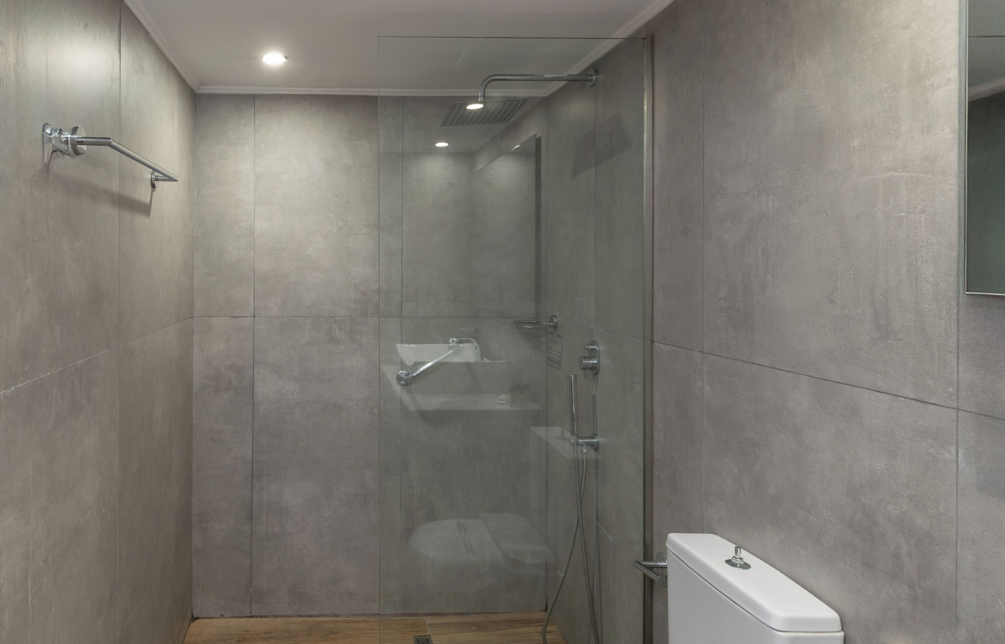 Une douche moderne dotée d’une paroi en verre, d’un pommeau de douche à main et d’un porte-serviettes fixé au mur.