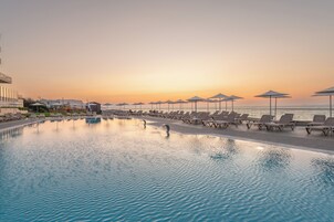 Una piscina al aire libre, sombrillas, sillones reclinables de piscina