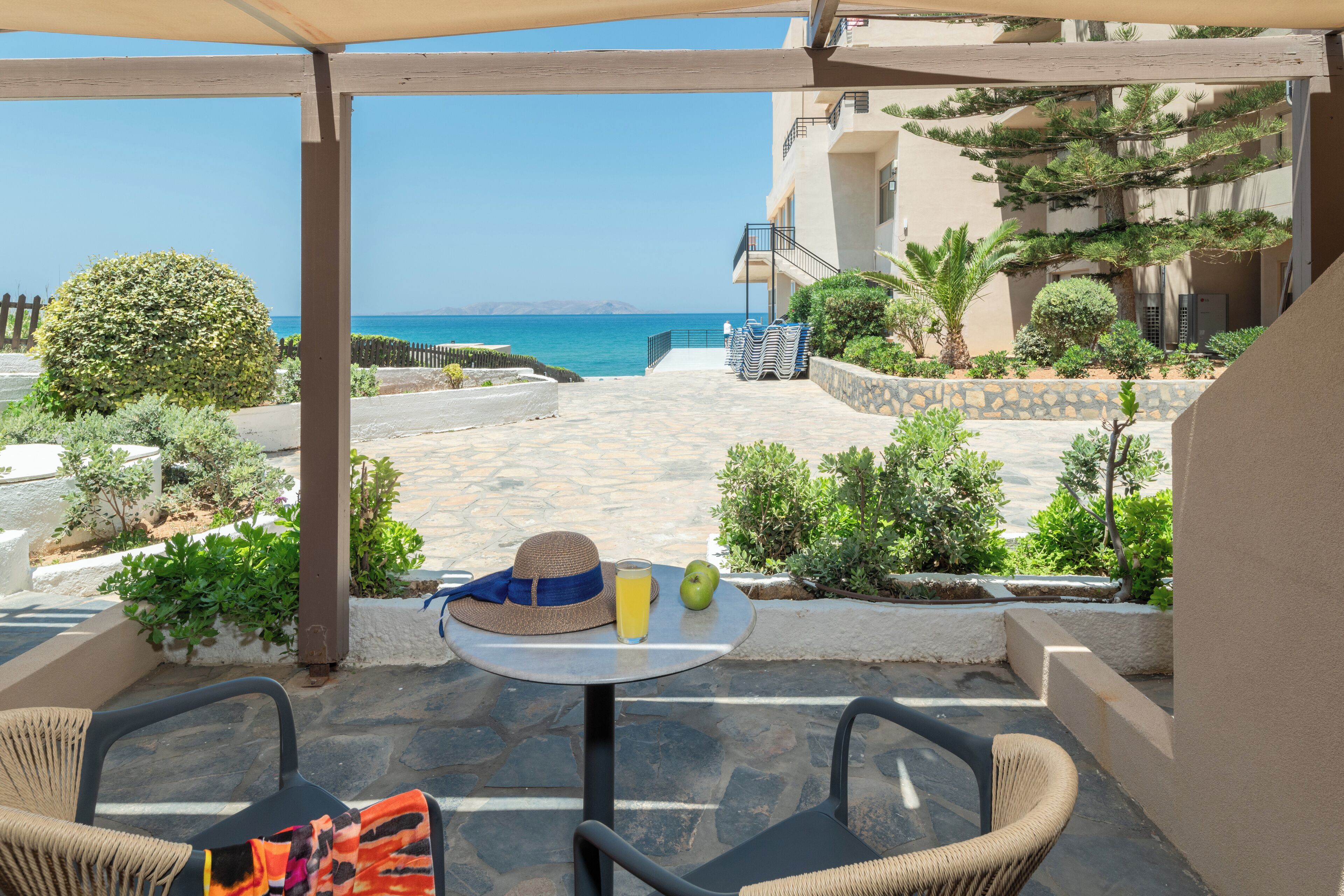 A patio with a table, chairs, and a view of the sea.