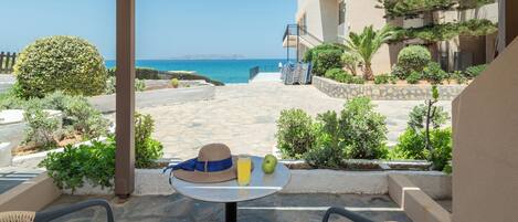 A patio with a table, chairs, and a view of the sea.
