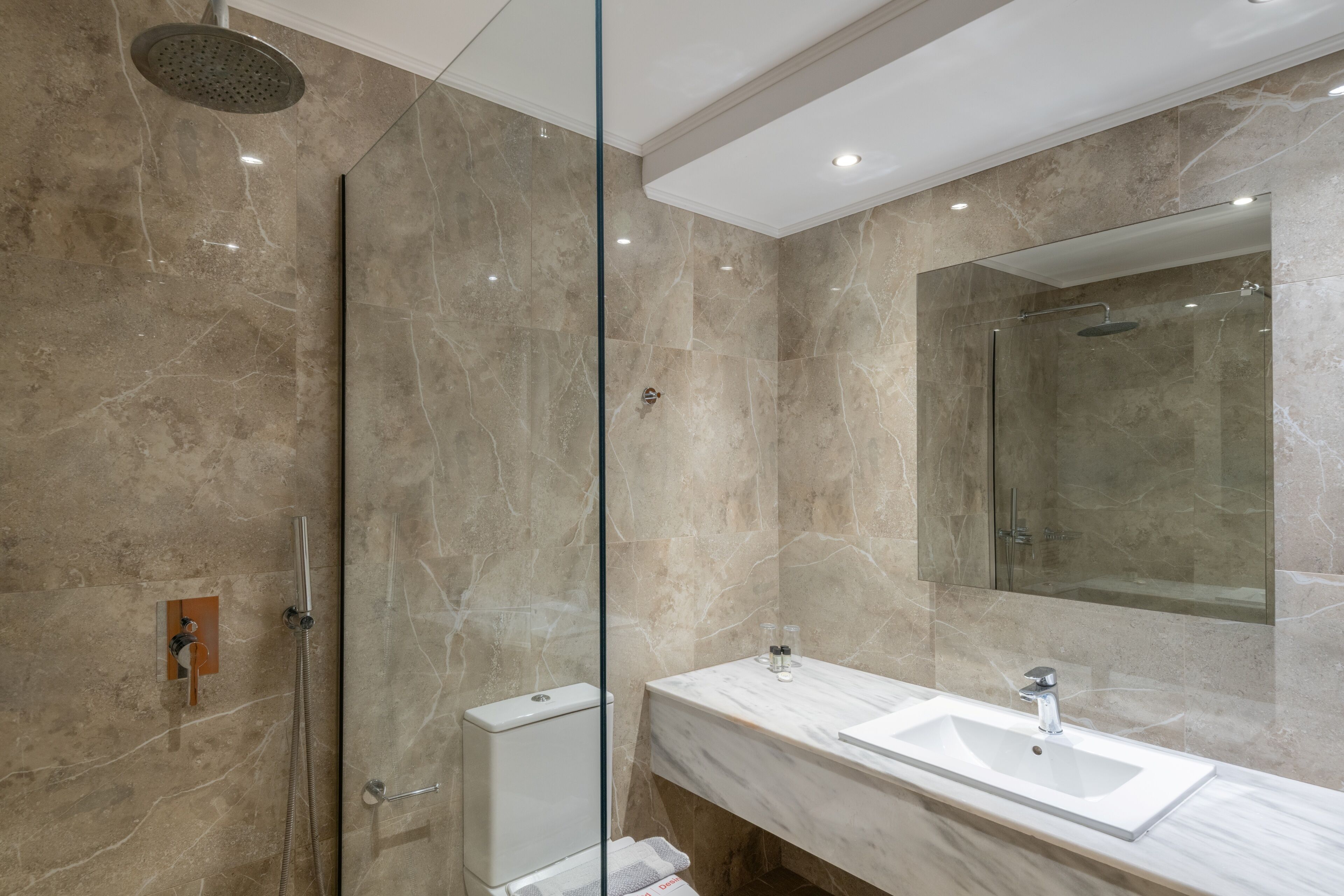 Een moderne badkamer met een douchecabine van glas, een witte wastafel en een grote spiegel.