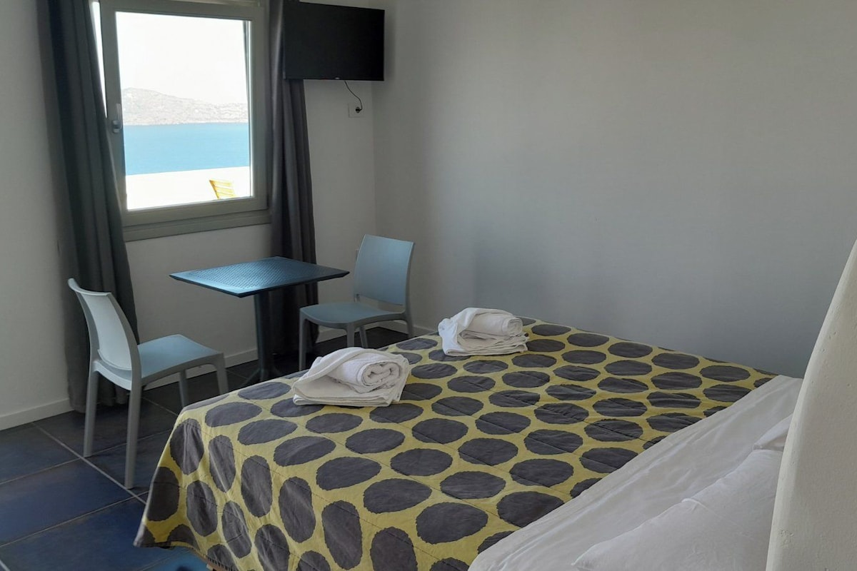 A hotel room with a bed, a desk, a chair, and a TV.