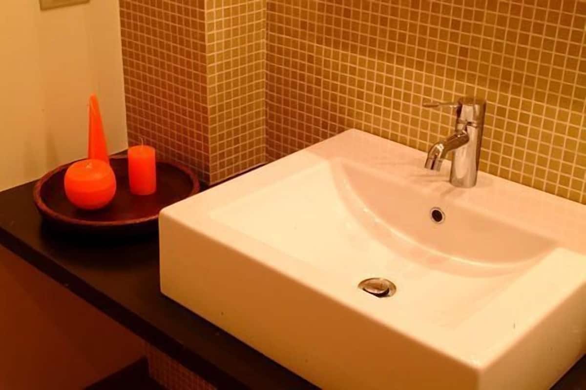 A bathroom with a white sink, a silver faucet, and a dark countertop.