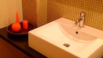 Un baño con lavamanos blanco, encimera oscura y pared de azulejos.