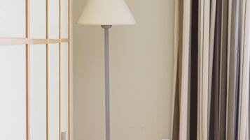 Ein Zimmer mit einer Stehlampe, einem Vorhang und einer Wand mit einem gitterartigen Muster.