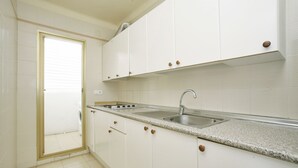 A kitchen with white cabinets, a granite countertop, and a stainless steel sink. - Apartamentos Pins Marina Cambrils (Cambrils)