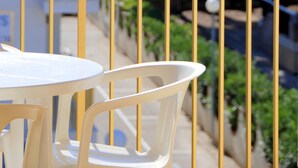 A balcony with yellow railings, white plastic chairs, and a view of the beach and ocean. - Apartamentos Pins Marina Cambrils (Cambrils)
