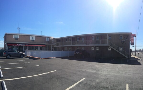 A multi-story building with a parking lot in front. - Anchor Motel (Seaside Heights)