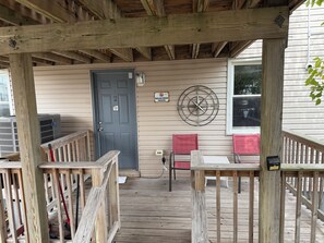 A wooden deck with a covered porch, a door, a compass wall decoration, and a red chair. - Anchor Motel (Seaside Heights)