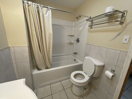 Un baño con bañera, inodoro y cortina de ducha.