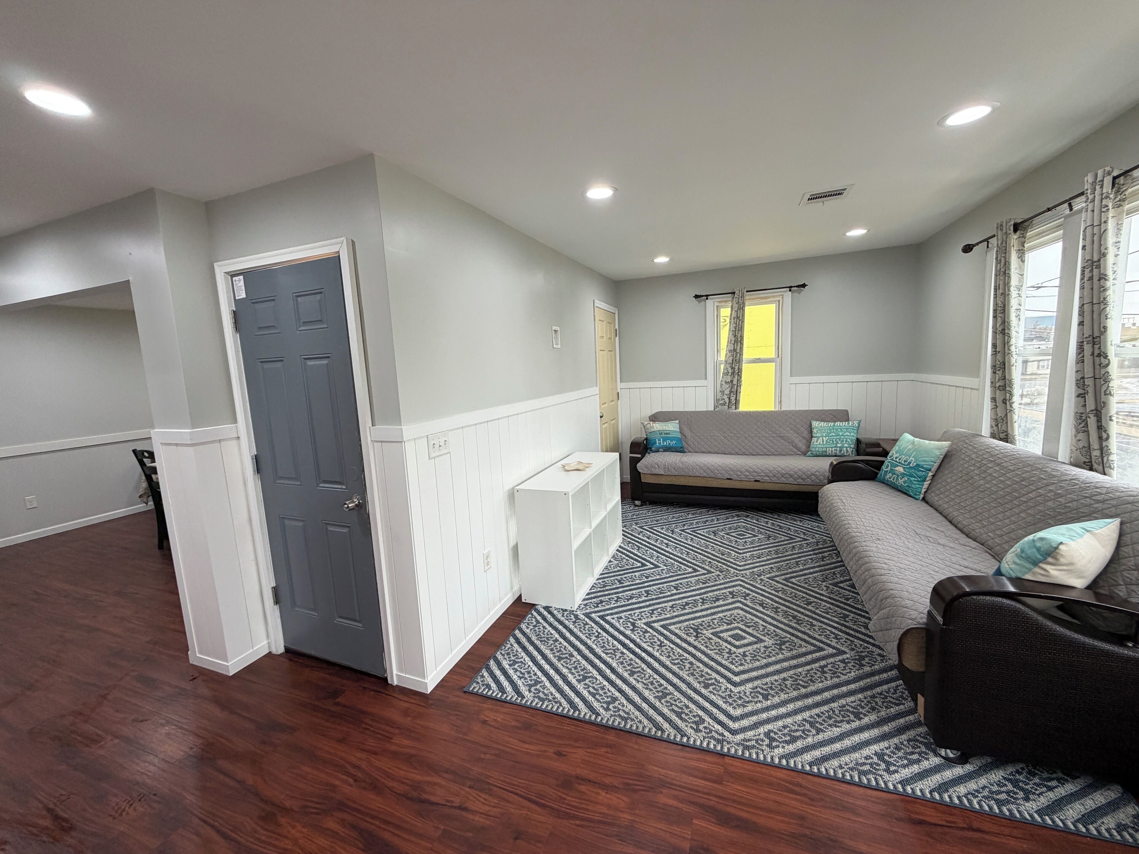 A modern living room with a grey sofa, patterned rug, and a small white side table.