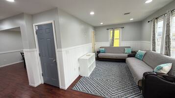 A modern living room with a grey sofa, patterned rug, and a small white side table.