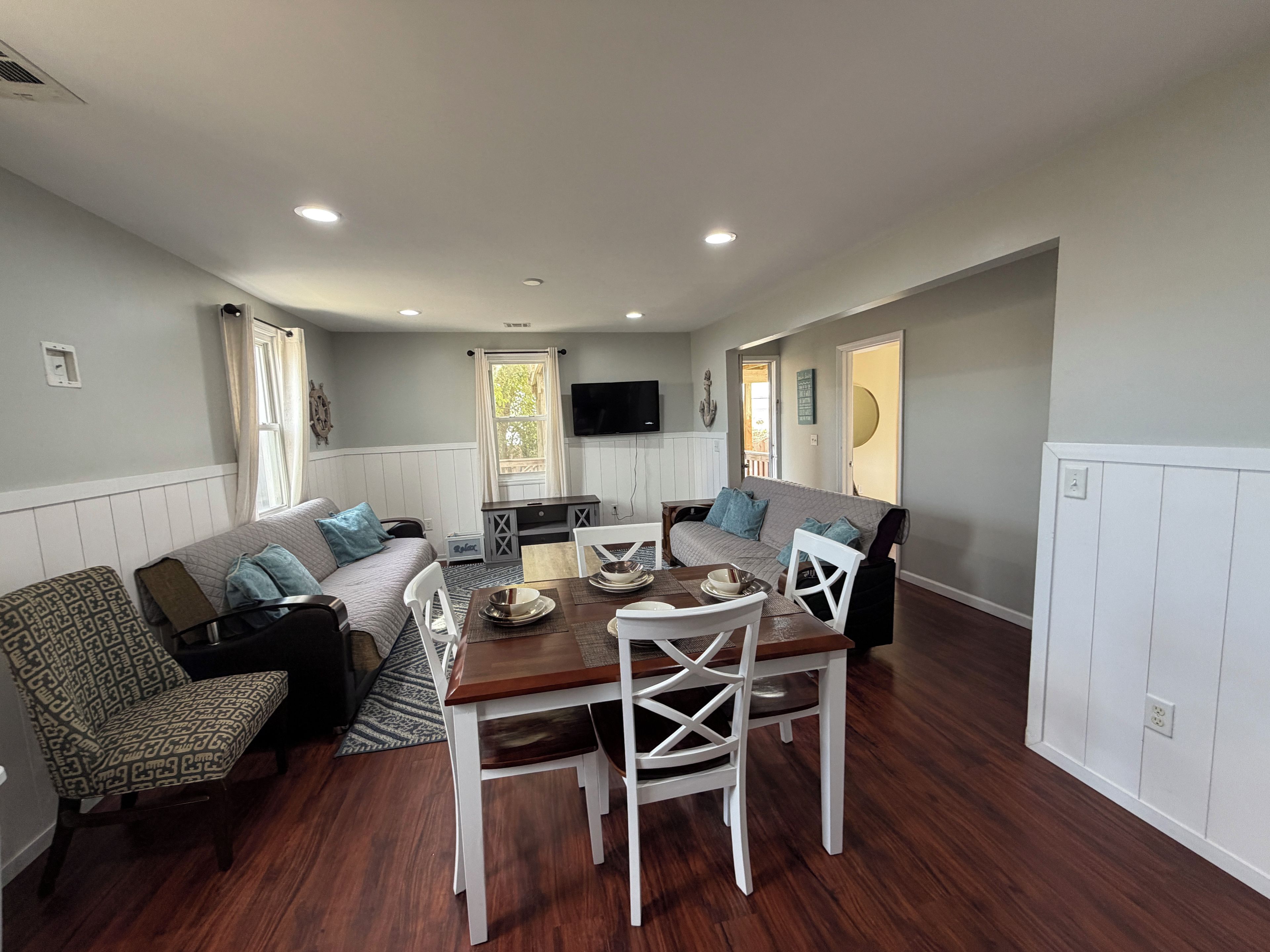 A compact living space with a dining area, sofa, and a television mounted on the wall.