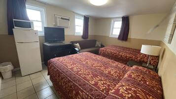 Une chambre d’hôtel avec deux lits, un réfrigérateur, une télévision, un bureau et une fenêtre avec des rideaux.