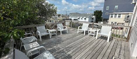 A wooden deck with white chairs and a doormat with "WELCOME" on it.